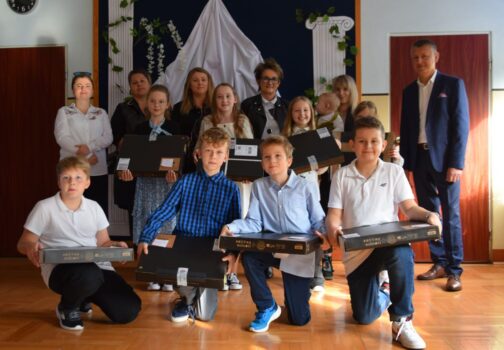 Uczniowie czwartej klasy w szkole w Małyszynie z otrzymanymi laptopami