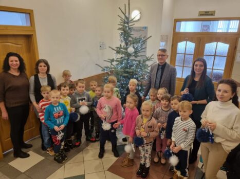 Uczniowie Szkoły Podstawowej w Mircu wraz opiekunkami i wójtem Miroslaweem Sewerynem przy świątecznym drzewku w Urzędzie Gminy w Mircu,